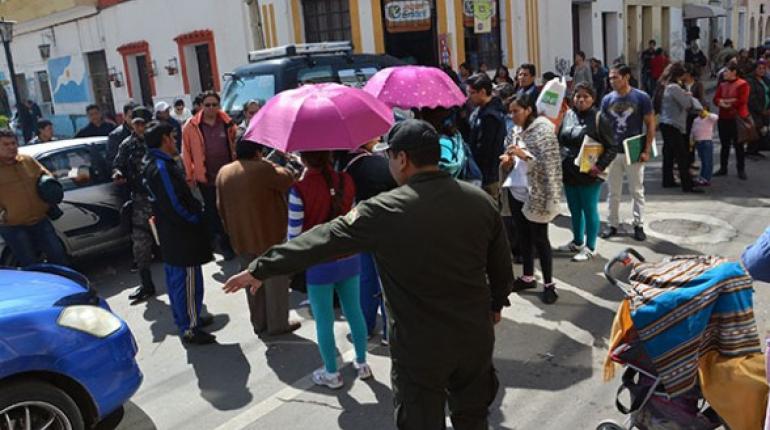 Policías desvían el tránsito ante el bloqueo de una calle por los padres que querían un cupo para inscribir a sus hijos.